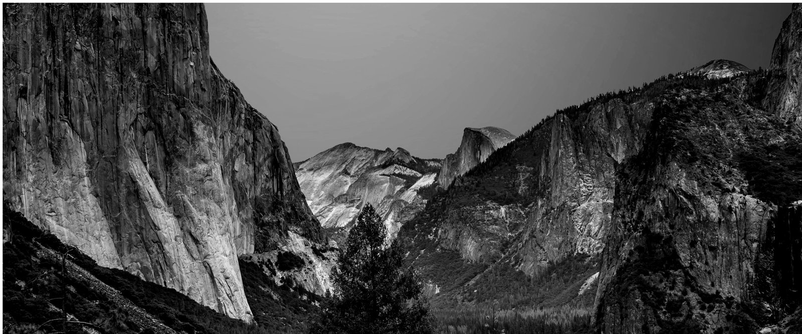 Yosemite Valley in black and white: granite cliffs either side, Half Dome in the distance.
